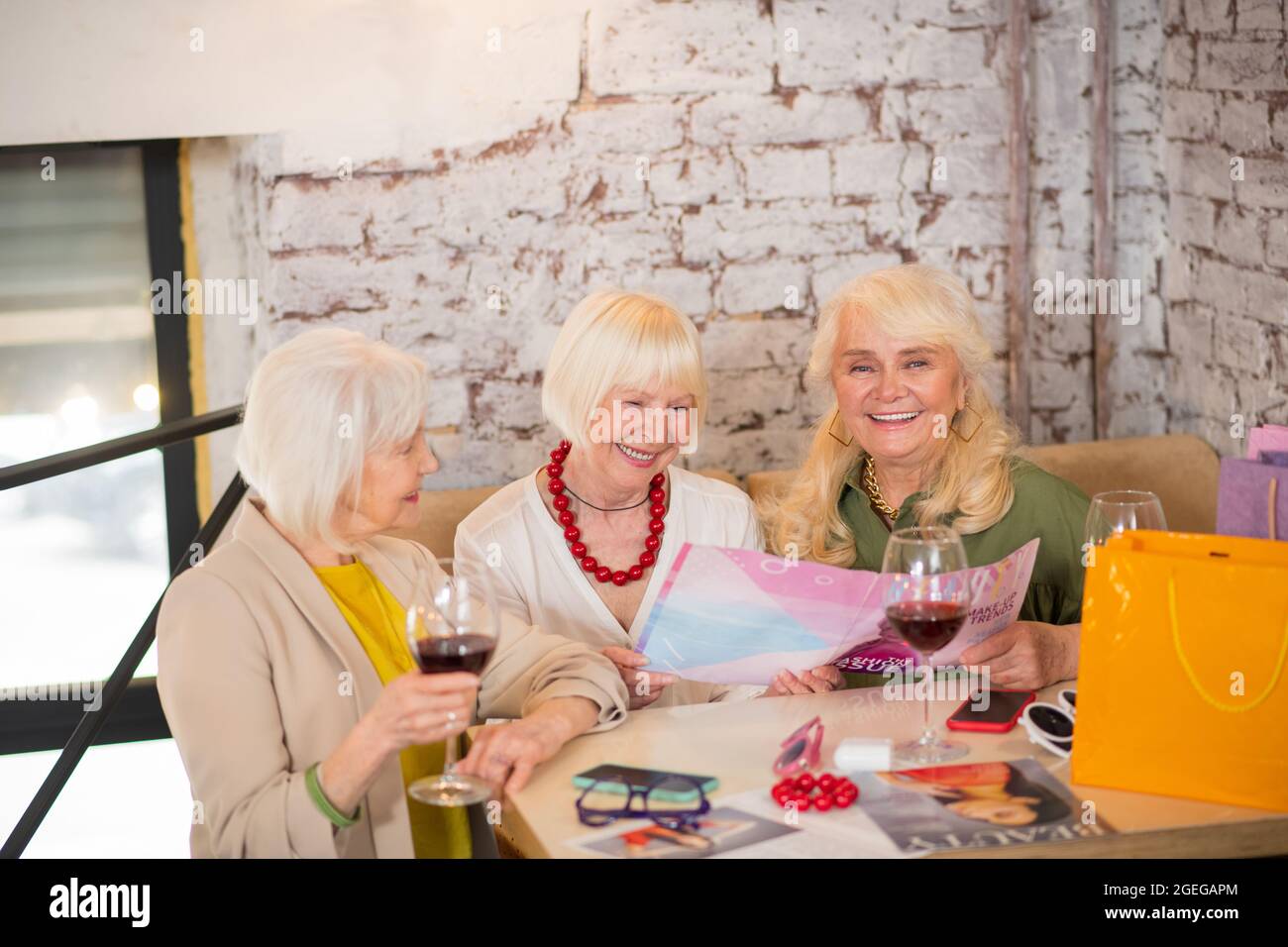 Trois femmes matures assises à la table et regardant excitée Banque D'Images