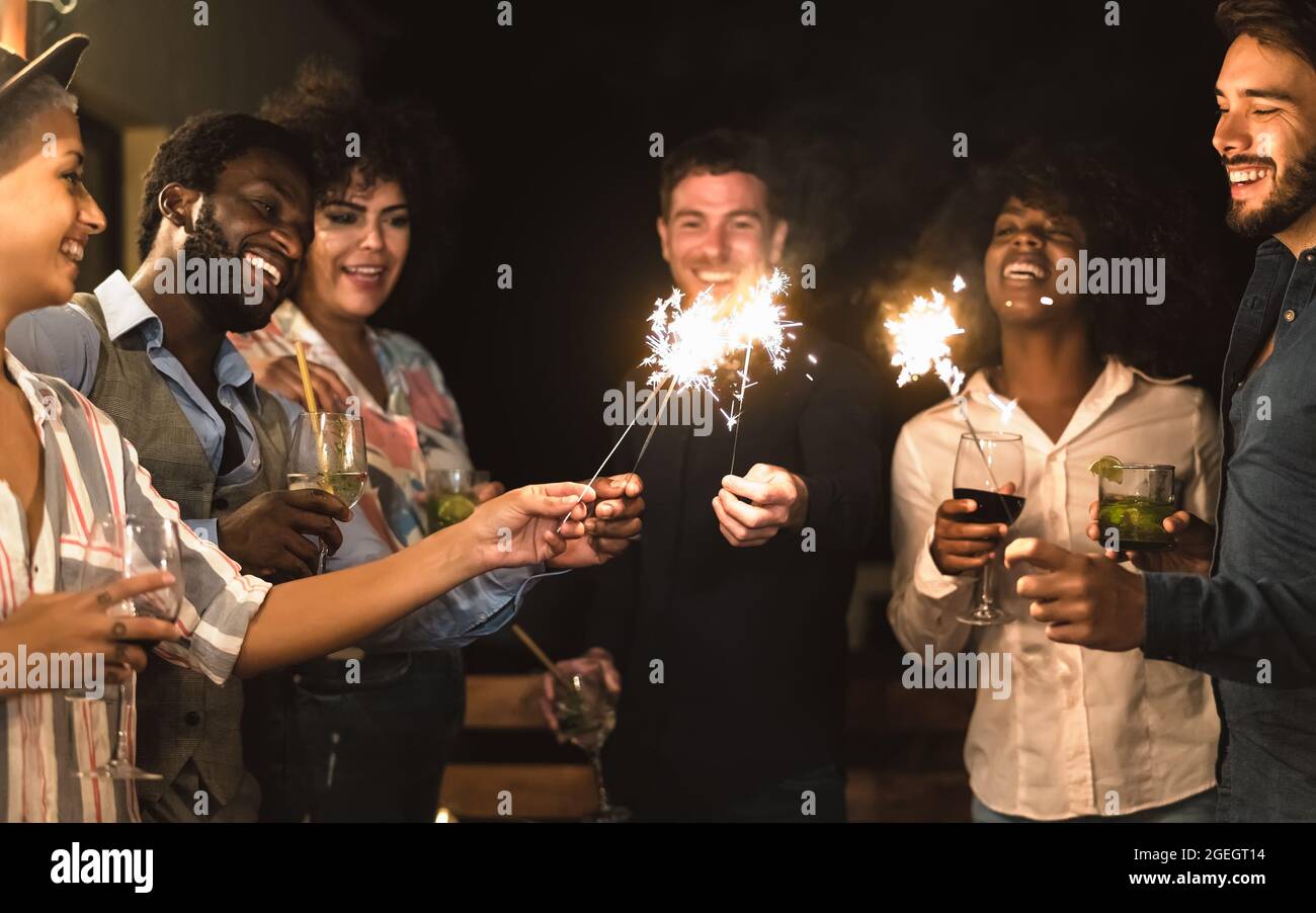 Des jeunes amis heureux s'amuser avec des feux d'artifice et de boire des cocktails sur la maison patio partie - les jeunes gens style de vie et de vacances concept Banque D'Images