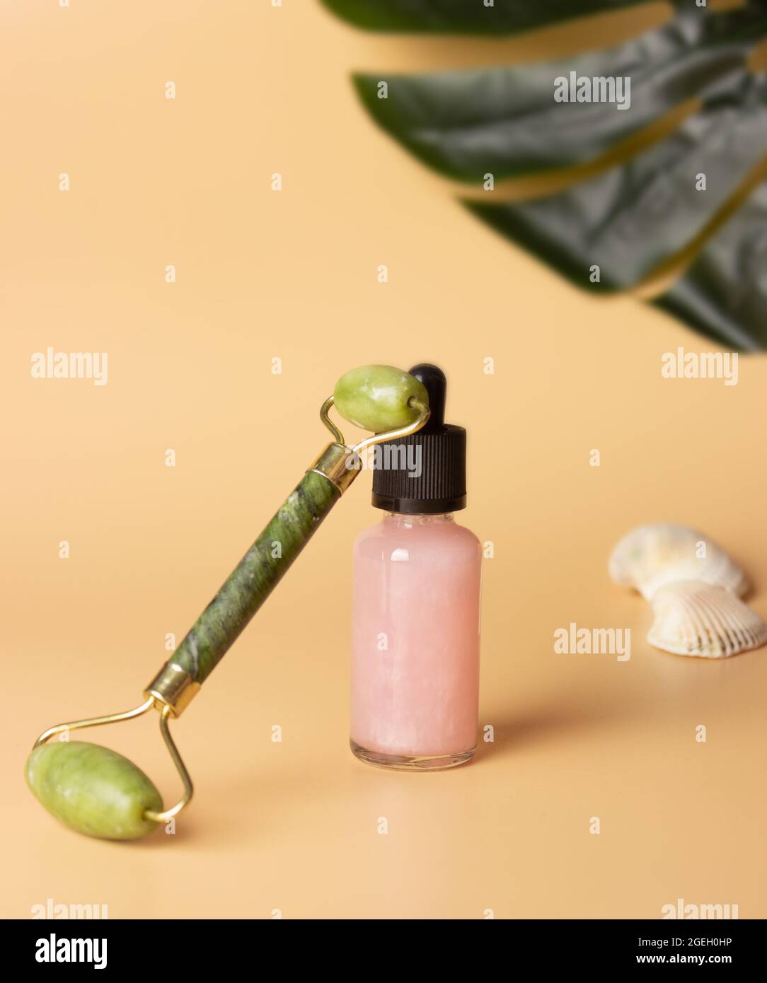 Une bouteille en verre avec une pipette et un produit cosmétique. Rouleau de quartz pour le massage du visage. Autosoins. Banque D'Images