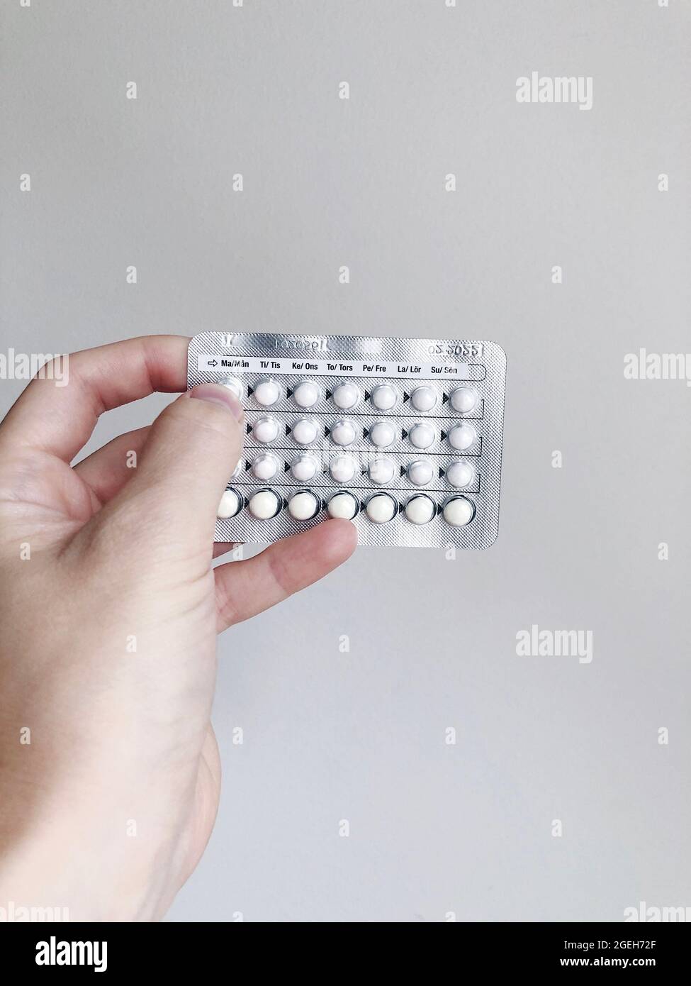 Une femme tenant des pilules contraceptives sur fond blanc Banque D'Images