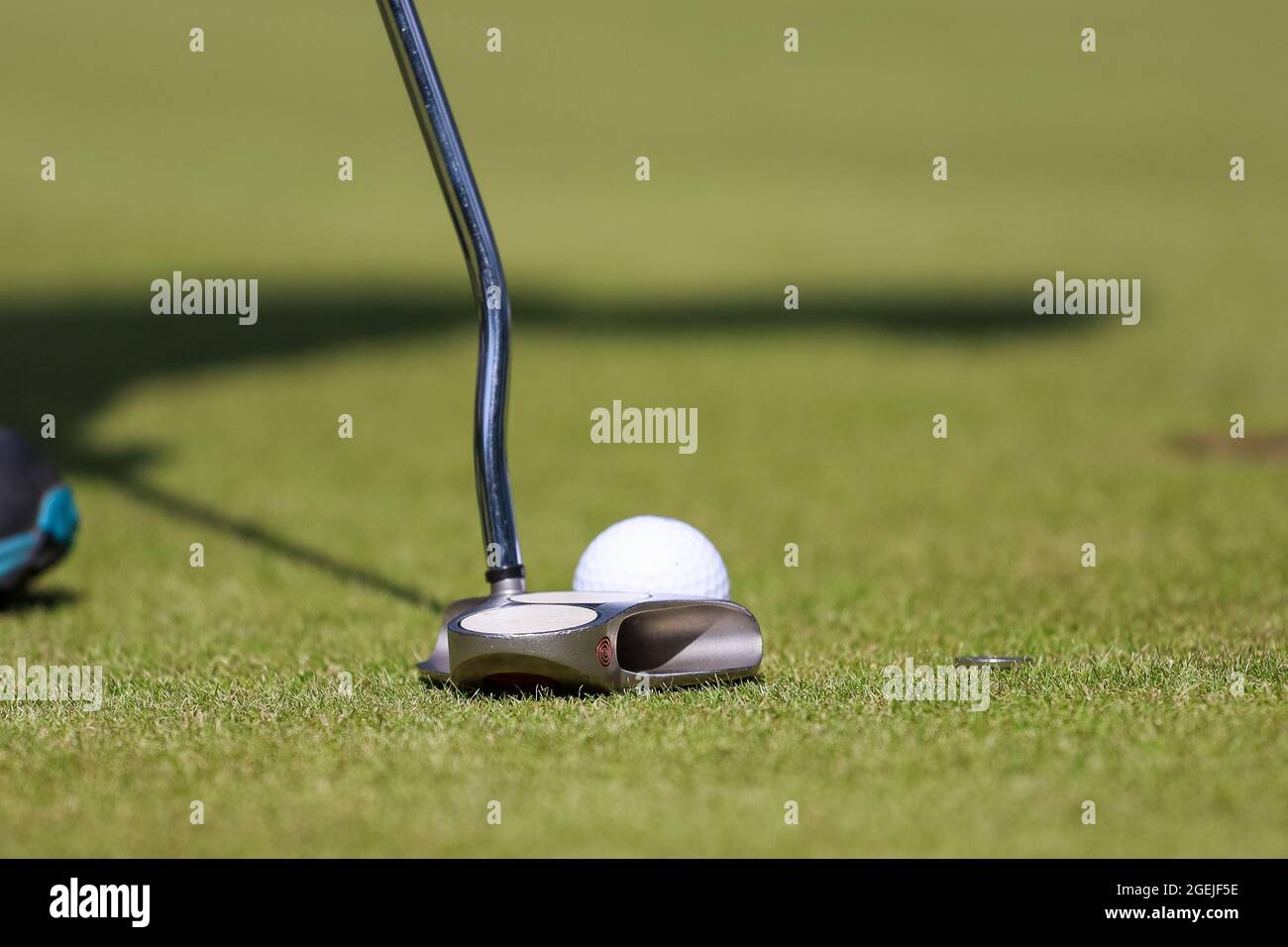 Partie basse de l'homme jouant au golf à l'aire d'échauffement sur un terrain vert Banque D'Images