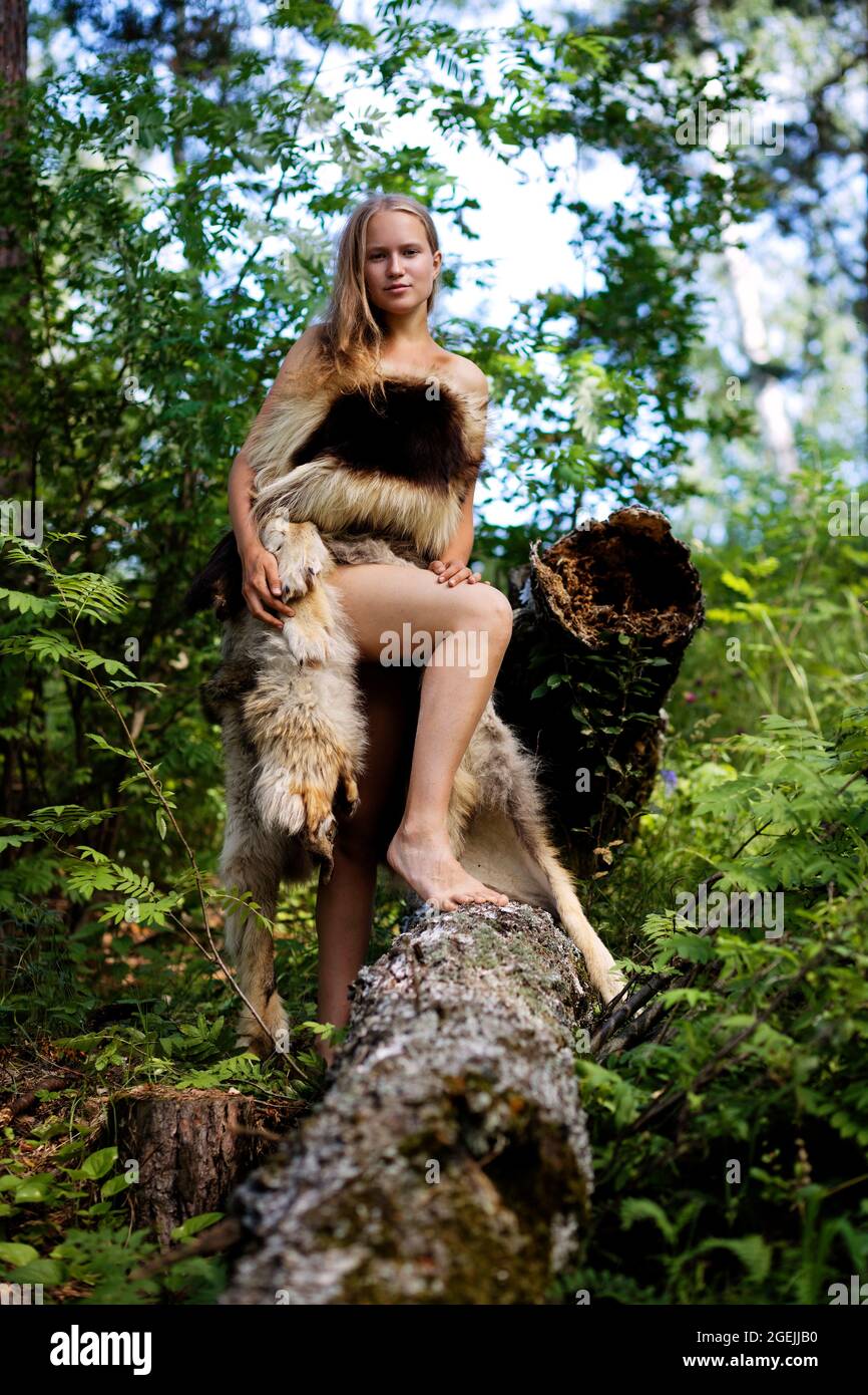 Fille sauvage vêtue de peaux d'animaux parmi les arbres de la forêt. Mise au point peu profonde. Banque D'Images