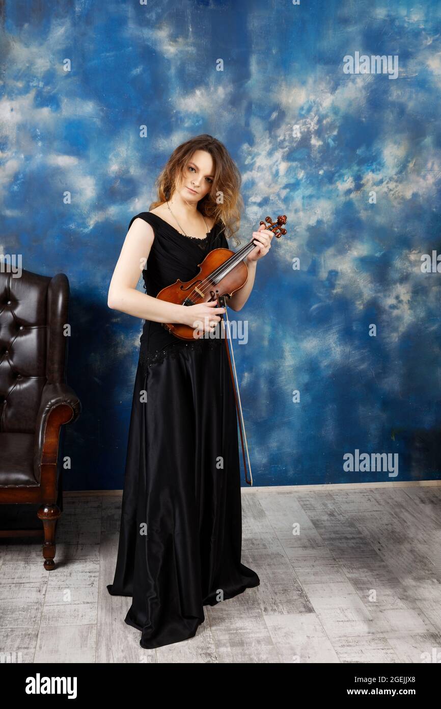 Jeune femme avec violon sur fond bleu abstrait. Banque D'Images
