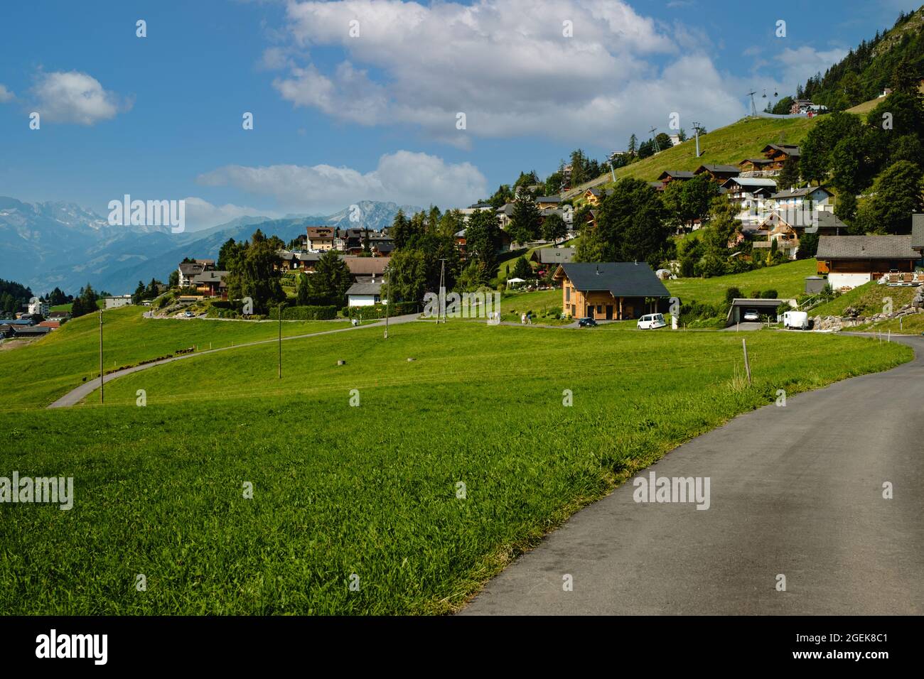 Route de montagne en béton et pâturages alpins verts dans la commune suisse de Leysin dans le canton de Vaud près d'Aigle, Suisse en été Banque D'Images