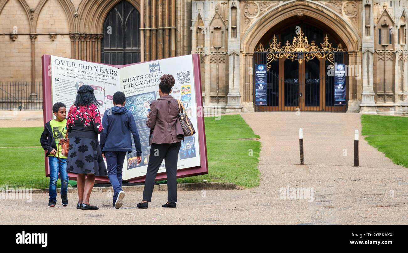 Une famille africaine a lu l'histoire au 13ème siècle face ouest de la cathédrale chrétienne médiévale de Peterborough, Angleterre. Banque D'Images