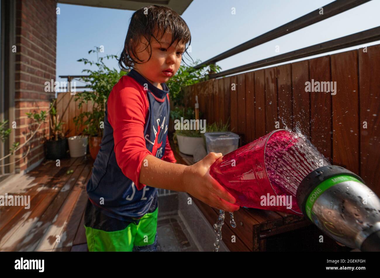 un garçon s'mouille en été sur sa terrasse Banque D'Images