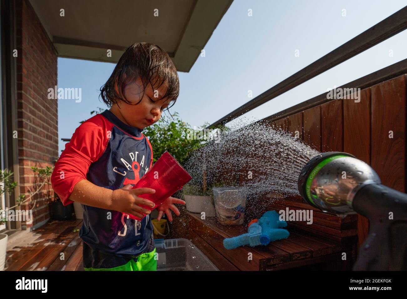 un garçon s'mouille en été sur sa terrasse Banque D'Images