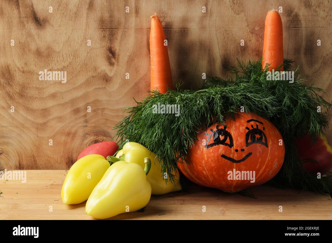 Citrouille drôle avec les yeux peints et un sourire sur un fond en bois dans la décoration de l'aneth et des légumes. Mise au point sélective. Banque D'Images