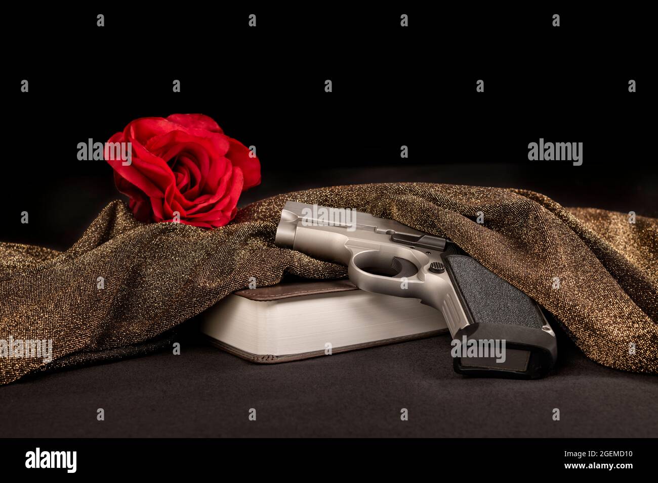 Dans le cadre d'une organisation criminelle, cette image représente une rose rouge symbolique derrière une bible et un fusil, un rituel prémeurtrier des hommes à frapper mafieux. Banque D'Images