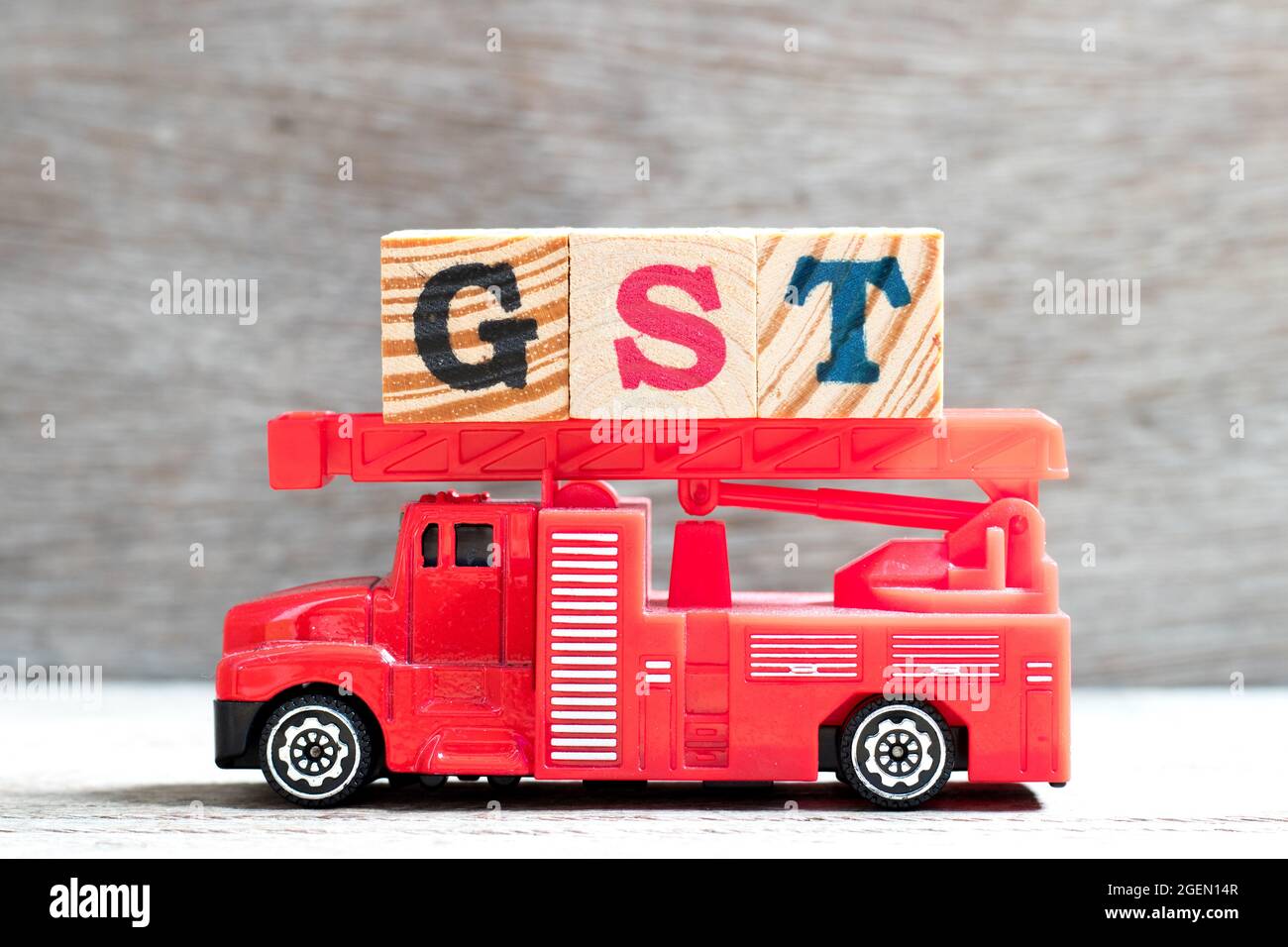 Jouet échelle incendie camion tenir le bloc de lettres dans le mot TPS (abréviation de taxe sur les produits et services) sur fond de bois Banque D'Images