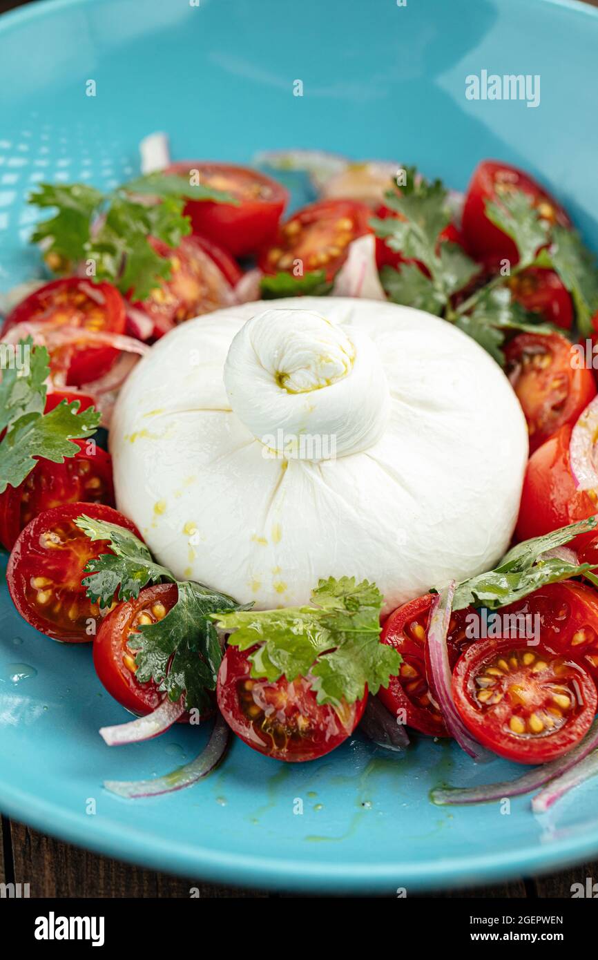 Salade de fromage burrata avec pommes de terre dans une assiette bleue Banque D'Images