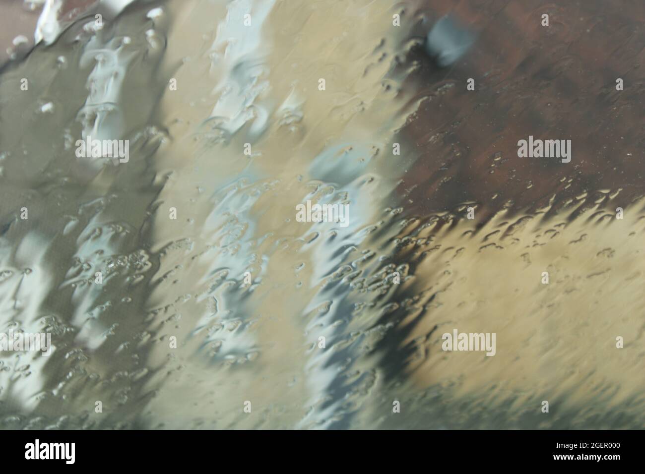 Les bâtiments sont vus par une fenêtre recouverte de pluie, ce qui se traduit par un arrière-plan abstrait texturé Banque D'Images