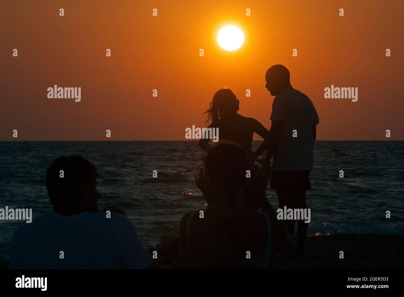 Rome, Italie. 21 août 2021. 20 août 2021 : UN couple est debout sur la plage du col sombre dans la ville de Rome pendant le coucher de soleil rouge-orange sur la mer Tyrrhénienne crédit: Agence de photo indépendante/Alamy Live News Banque D'Images