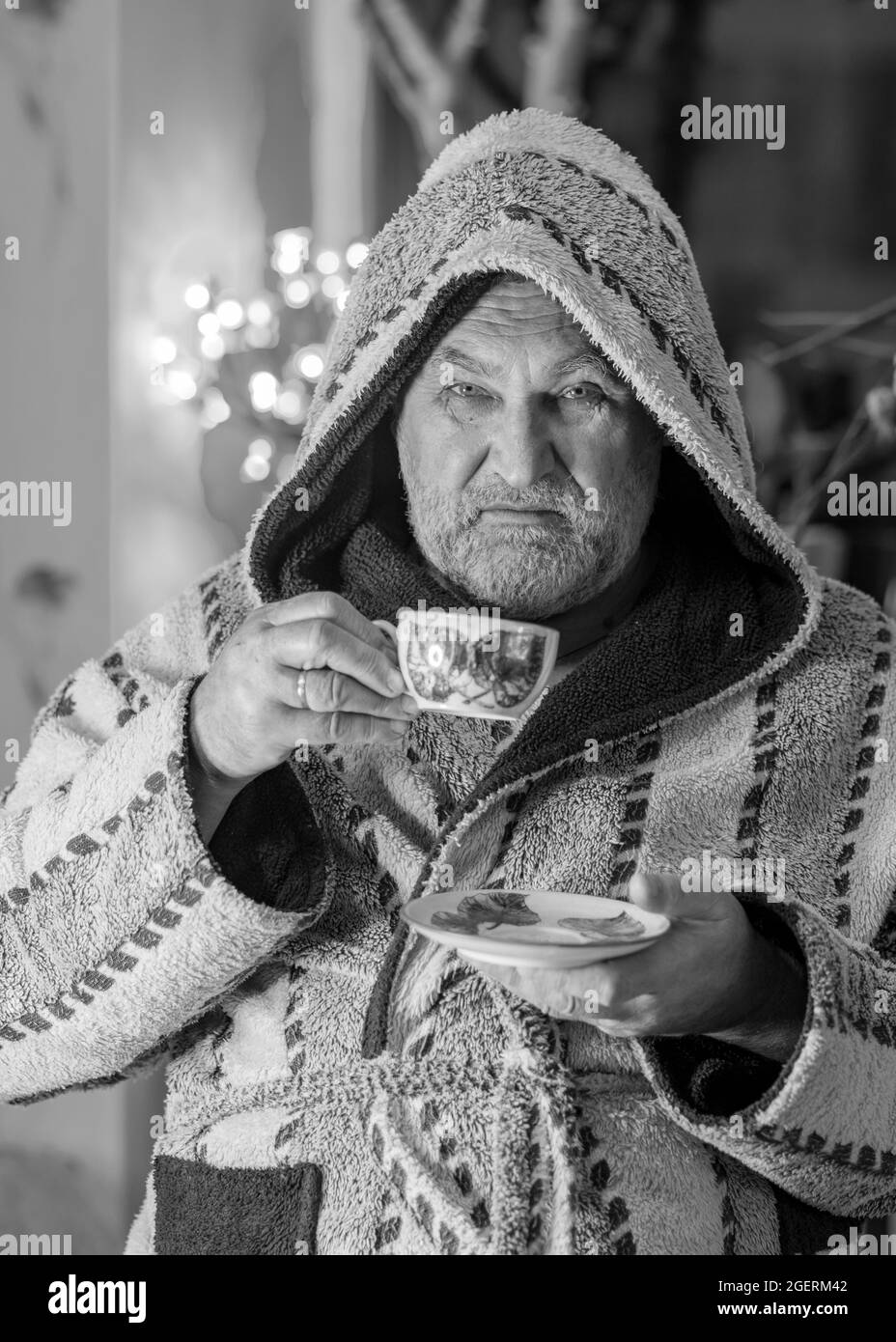 photo en noir et blanc d'un homme en robe boire un thé après un bain, portrait d'un homme, arrière-plan flou Banque D'Images