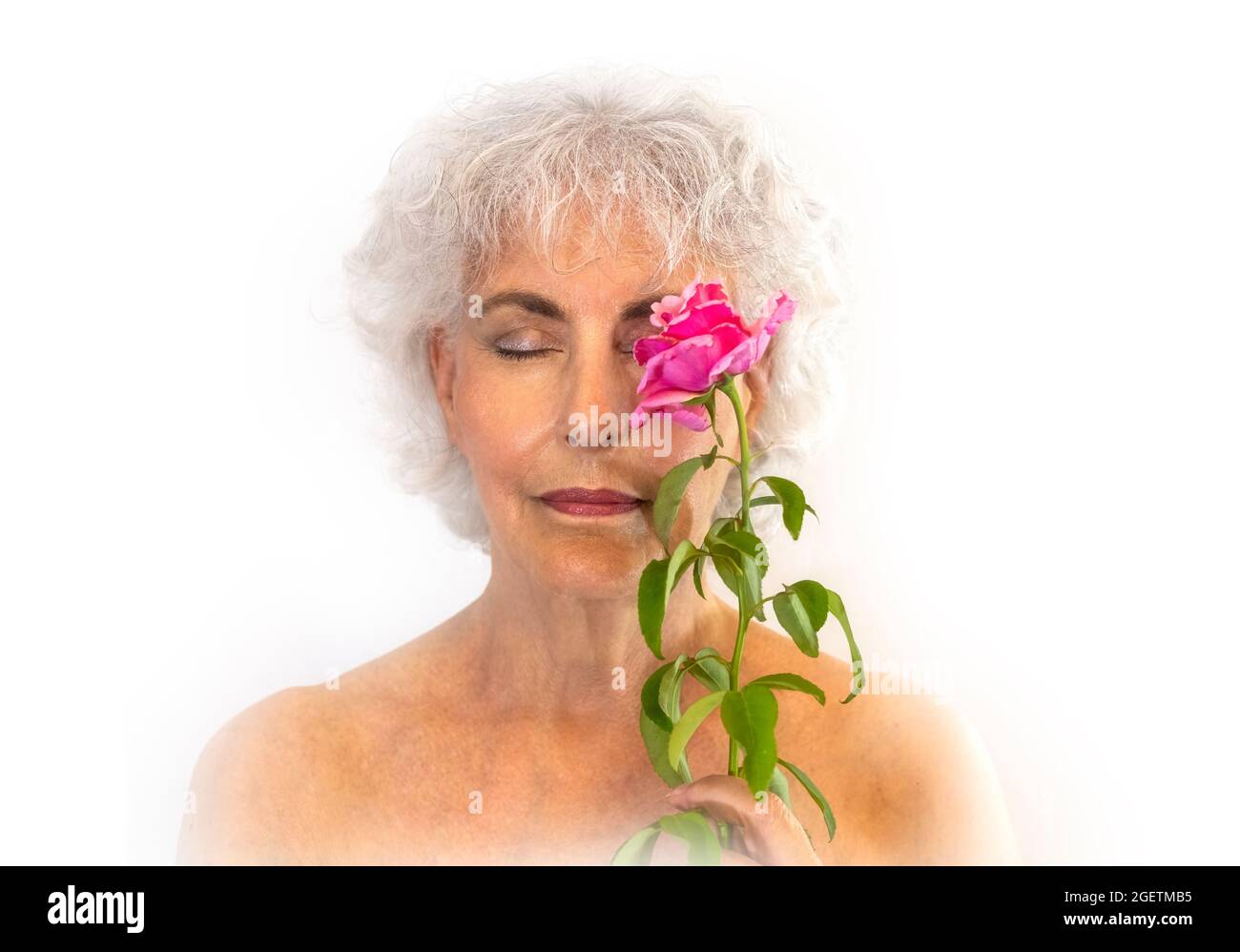 Portrait d'une femme âgée avec les yeux fermés, tenant une rose. Arrière-plan blanc. Banque D'Images