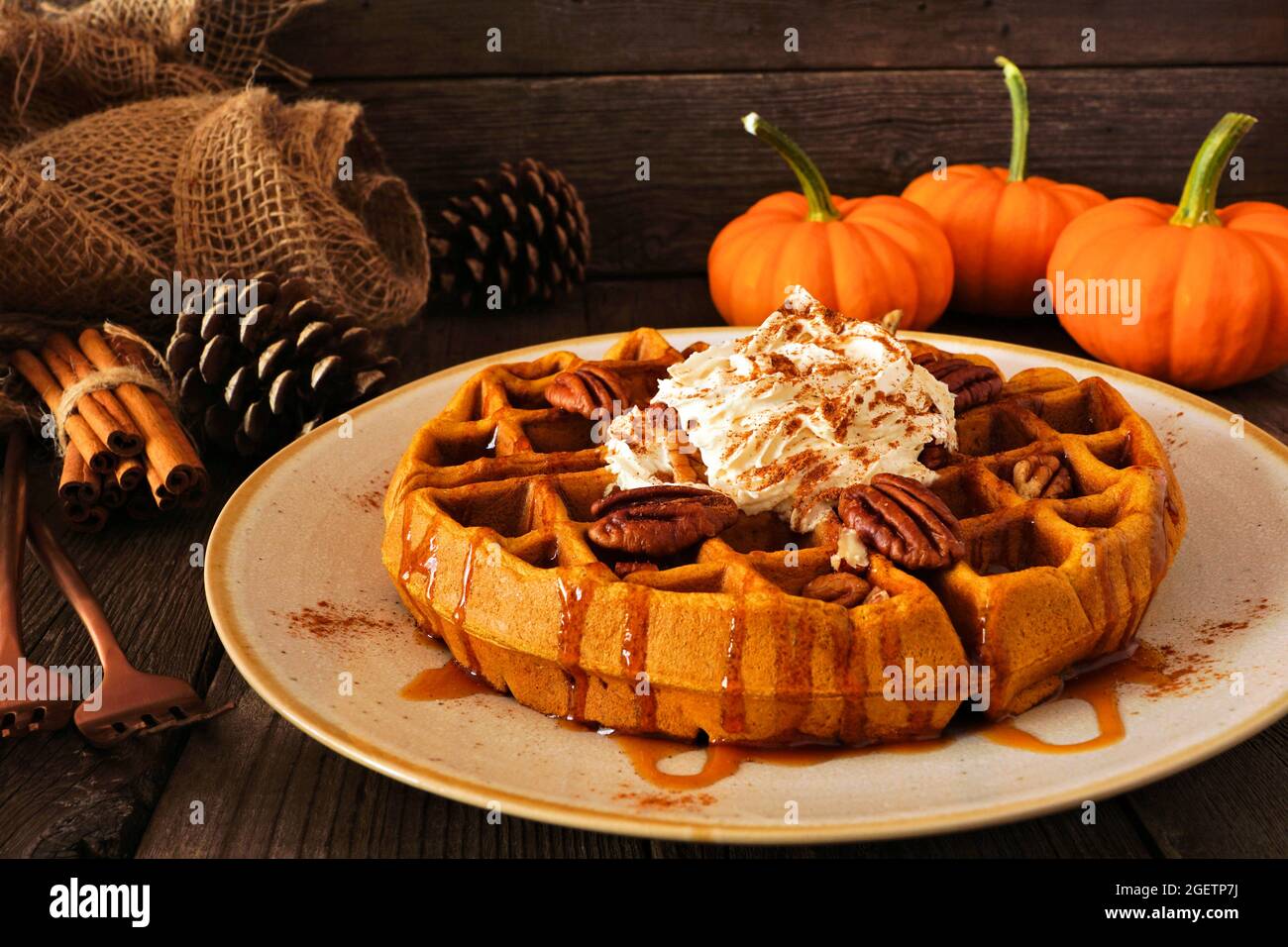 Gaufres aux épices à la citrouille avec garniture fouettée, caramel et pacanes. Vue latérale de la table avec un arrière-plan en bois sombre. Concept petit déjeuner automne. Banque D'Images