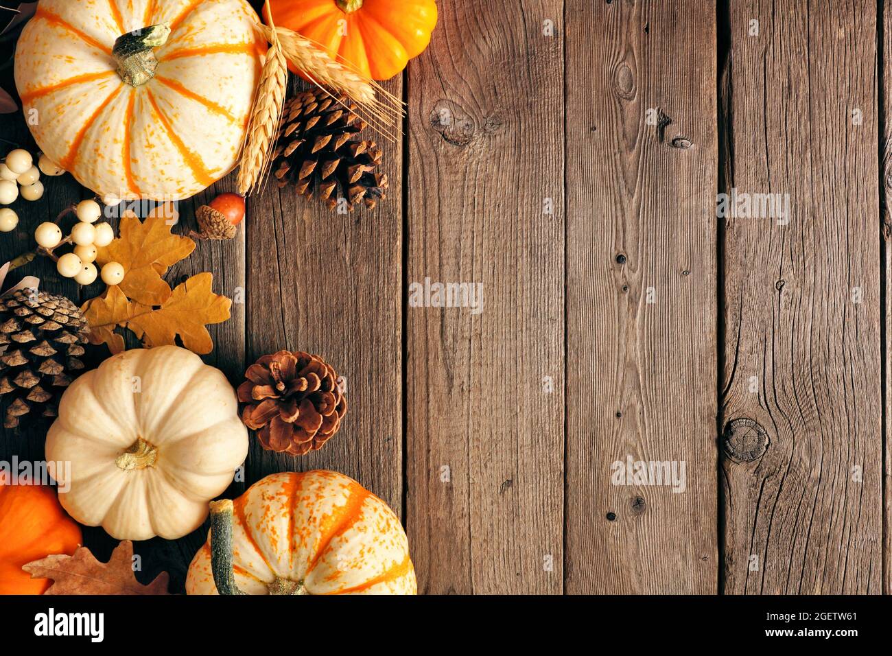 Bordure latérale d'automne naturelle des citrouilles et des feuilles. Vue de dessus sur un arrière-plan rustique en bois sombre avec espace de copie. Banque D'Images