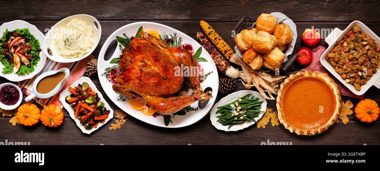 Dîner traditionnel de Thanksgiving avec dinde. Vue de dessus scène de table sur un arrière-plan de bannière en bois sombre. Dinde, purée de pommes de terre, vinaigrette, tarte à la citrouille et côté Banque D'Images