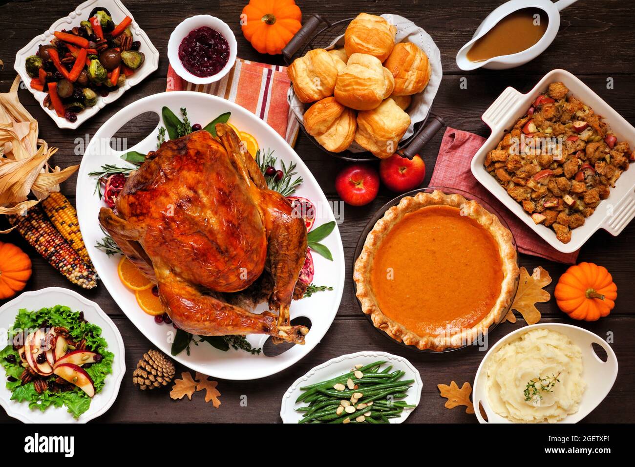 Dîner classique de Thanksgiving avec dinde. Scène de table au-dessus de la vue sur fond de bois sombre. Dinde, purée de pommes de terre, vinaigrette, tarte à la citrouille et accompagnements. Banque D'Images