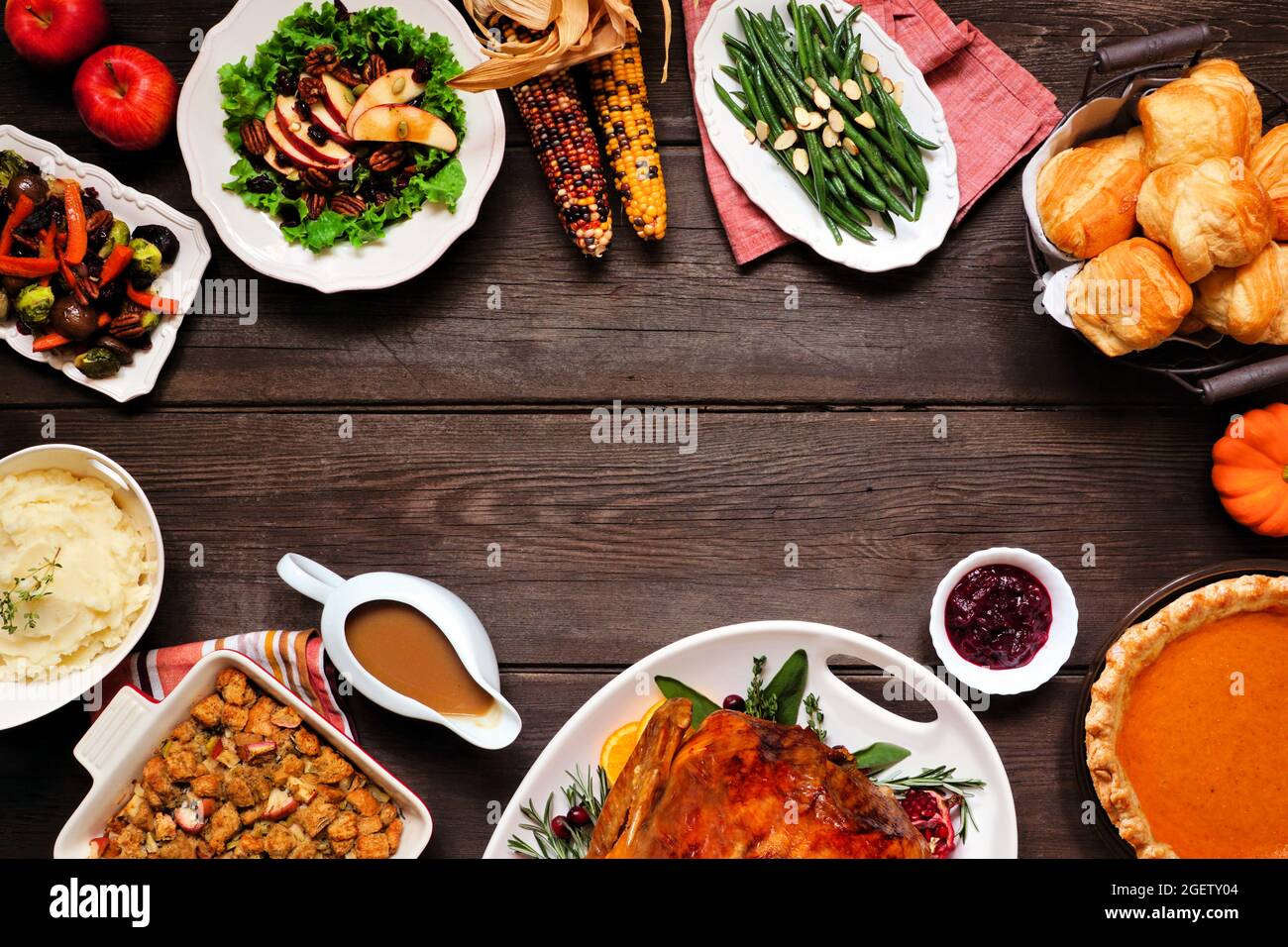 Dîner traditionnel de Thanksgiving avec dinde. Cadre de vue au-dessus de la tête sur un arrière-plan en bois sombre avec espace de copie. Dinde, purée de pommes de terre, vinaigrette, tarte à la citrouille Banque D'Images