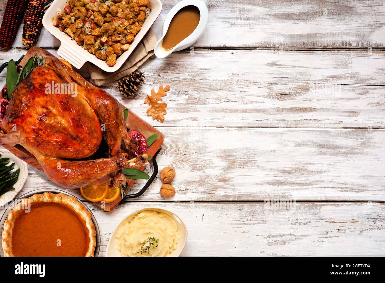 Dîner traditionnel de Thanksgiving avec dinde. Vue de dessus, bordure latérale sur un arrière-plan rustique en bois blanc avec espace de copie. Dinde, farce, purée de pommes de terre et Banque D'Images