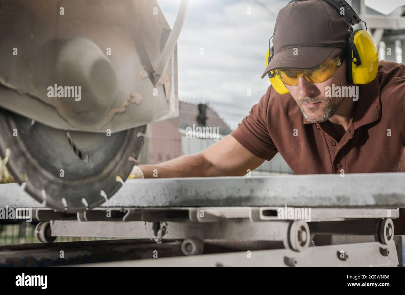 Béton chemin extérieur découpe de carreaux par un professionnel caucasien portant des lunettes de sécurité. Architecture extérieure thème de l'industrie. Banque D'Images