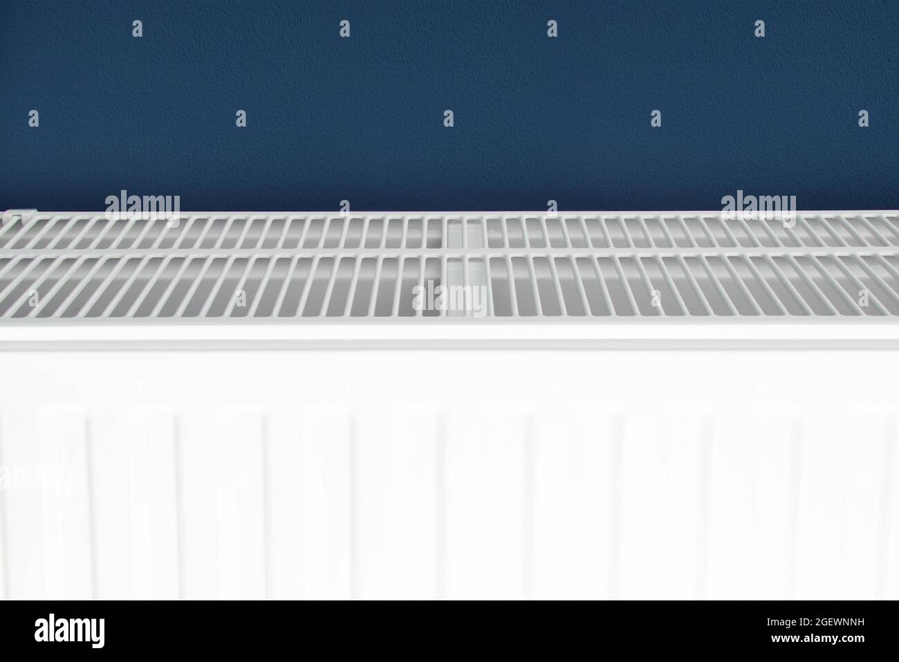 Radiateur de chauffage résidentiel blanc. Gros plan de l'élément du système de chauffage de l'eau domestique. Mur bleu foncé. Banque D'Images