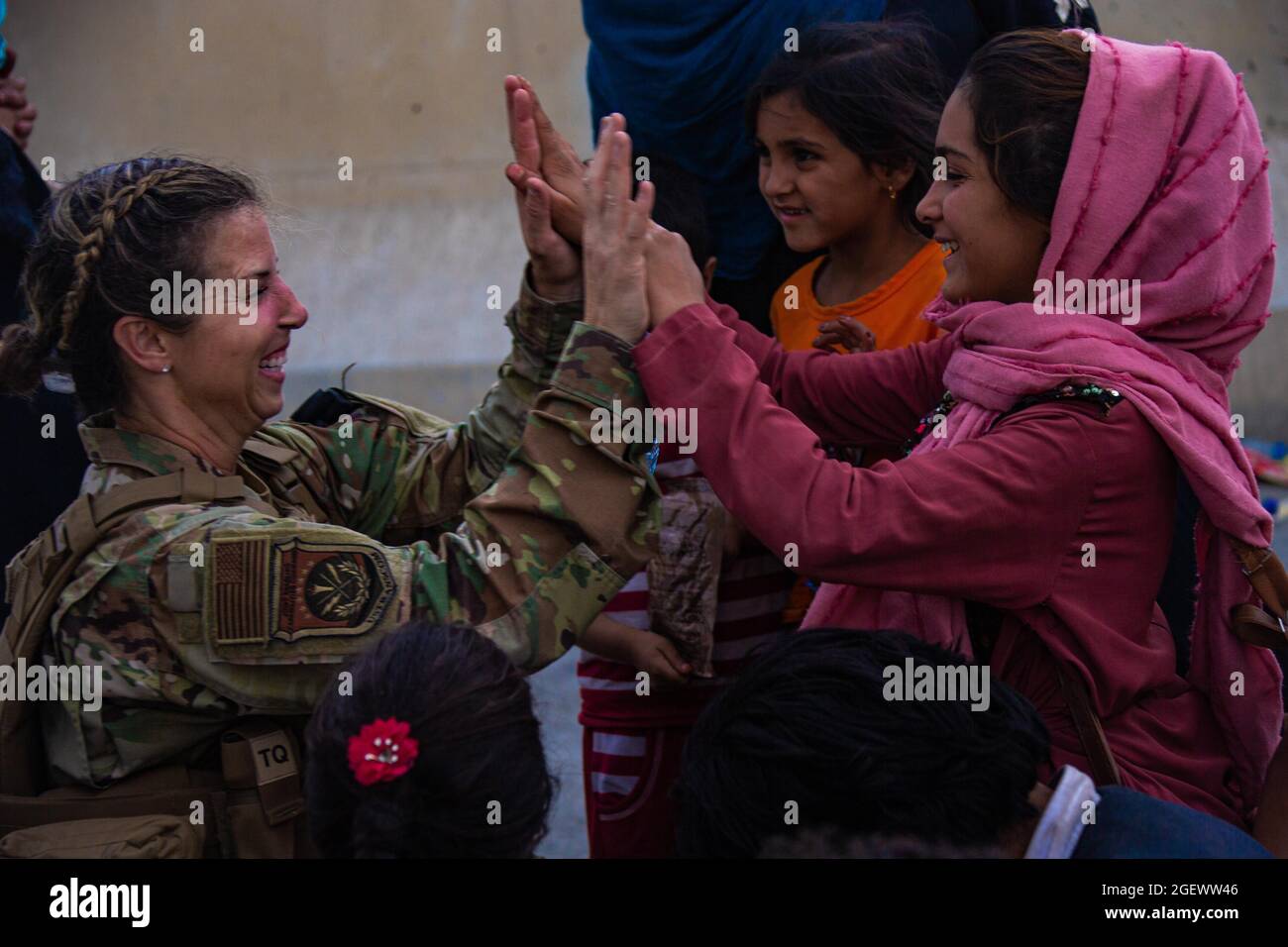 Un Airman des États-Unis avec la Force opérationnelle interarmées-réponse de crise élevé cinq enfants après avoir aidé à réunir leur famille à l'aéroport international Hamid Karzaï, Afghanistan, août 20. Les membres du service américain aident le ministère d'État à effectuer une opération d'évacuation non combattantes (NEO) en Afghanistan. (É.-U. Photo du corps marin par Cpl. Davis Harris) Banque D'Images