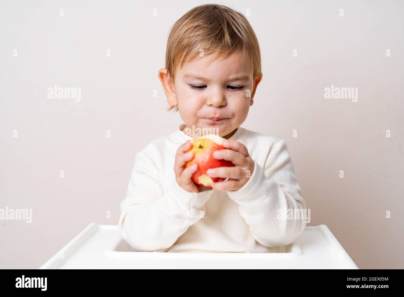 Bébé avec des pommes sur la chaise haute. Une alimentation saine. Récolte d'été et d'automne. Prise de vue en studio Banque D'Images