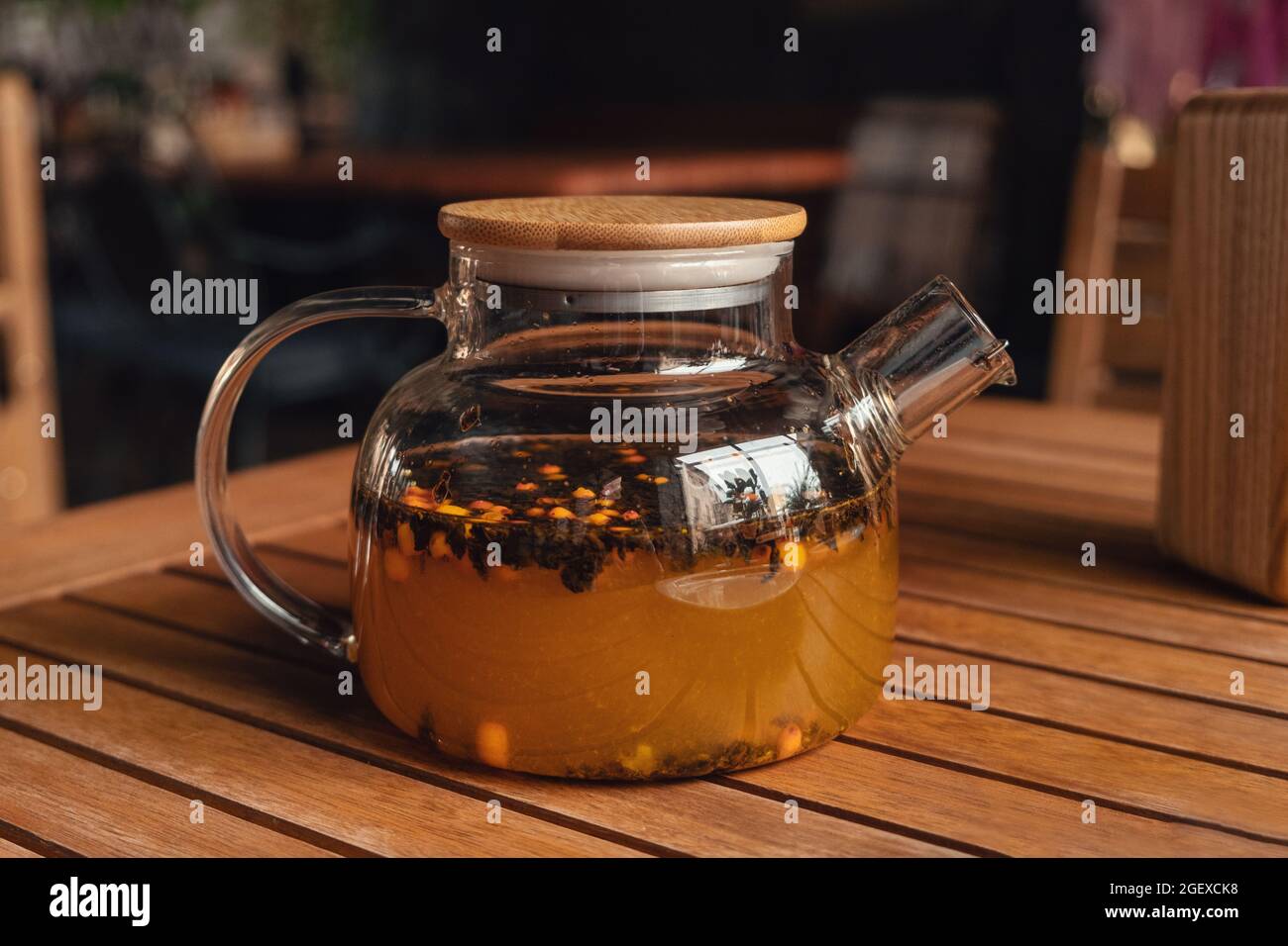 Thé réchauffant à l'argousier dans une théière en verre au café. Thé chaud par temps froid d'automne ou d'hiver - image Banque D'Images