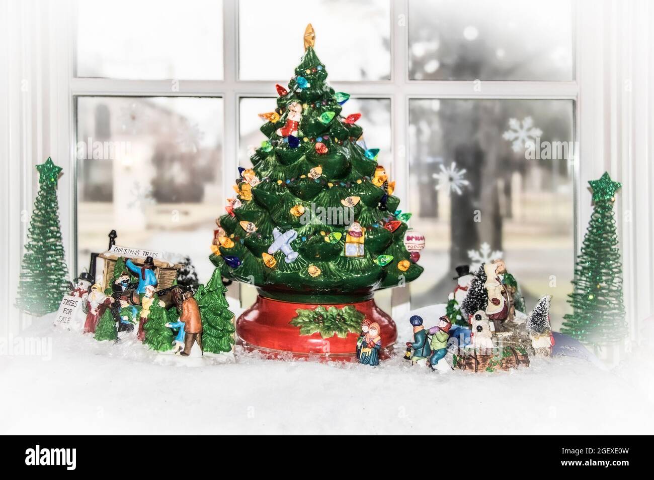 Scène du village de Noël installé dans une fenêtre avec un sapin de Noël rétro décoratif géant et des personnages extérieurs - mise au point sélective et bokeh Banque D'Images