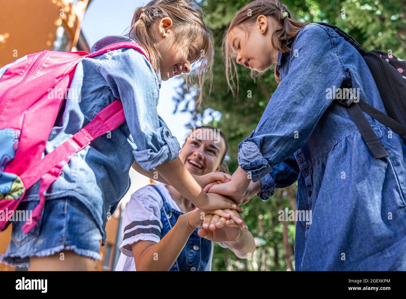 Une jeune femme soutient moralement les filles qui tiennent la main encourage les enfants, la mère accompagne les élèves à l'école. Banque D'Images