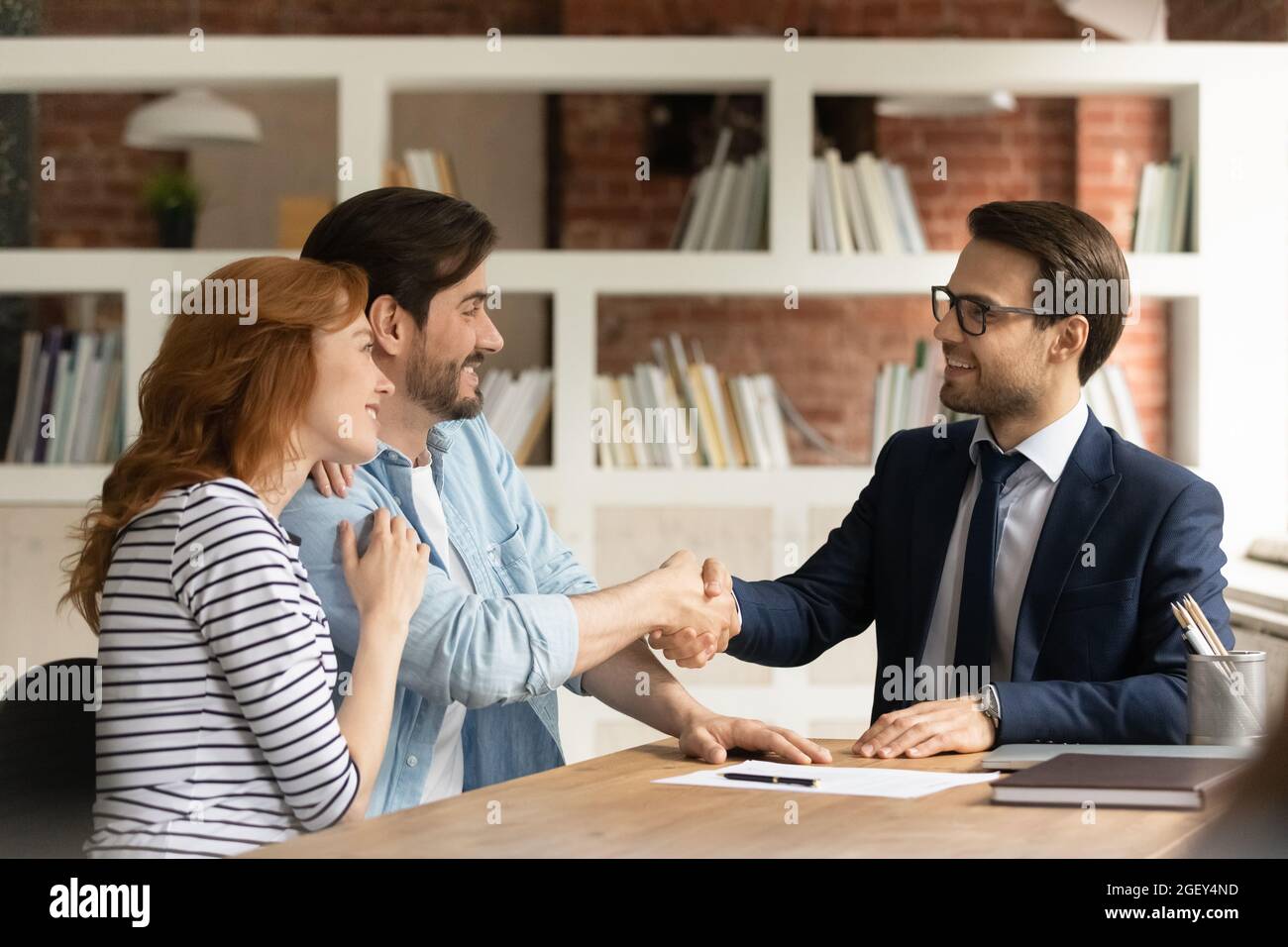 Couple poignée de main agent hypothécaire, acceptant les conditions et les taux de prêt bancaire Banque D'Images