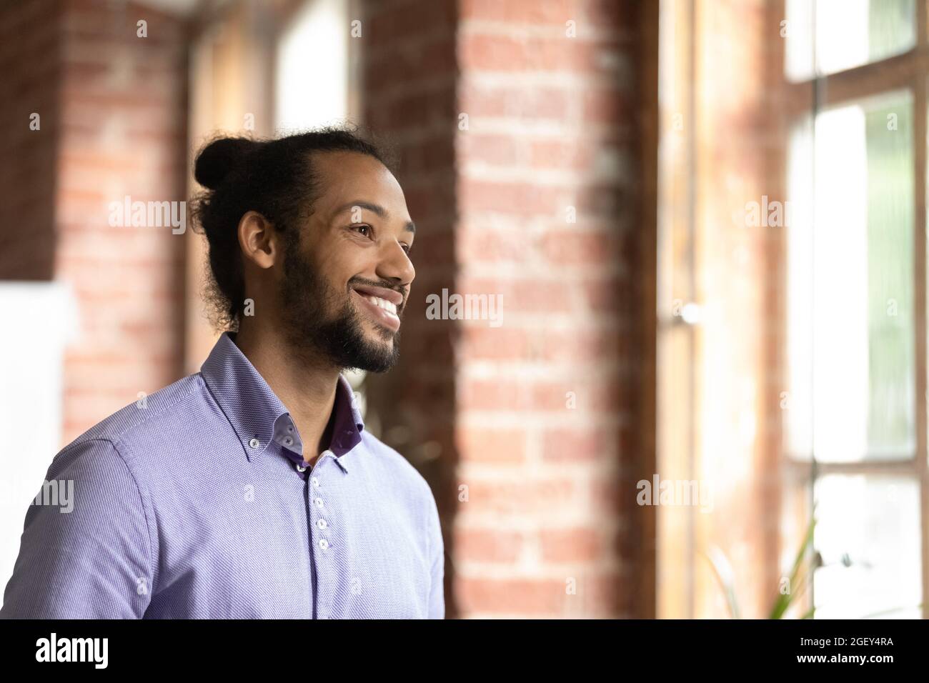Homme d'affaires africain souriant debout dans le bureau avec vue sur la fenêtre Banque D'Images