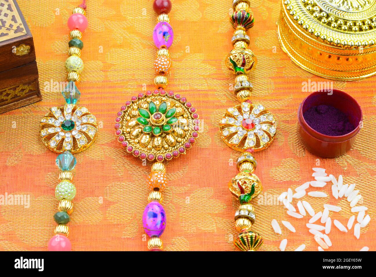 Fête hindoue indienne Raksha Bandhan. Rakhi coloré avec kumkum et riz sur fond de soie doré Banque D'Images Fête hindoue indienne Raksha Bandhan. Rakhi coloré avec kumkum et riz sur fond de soie doré Banque D'Images