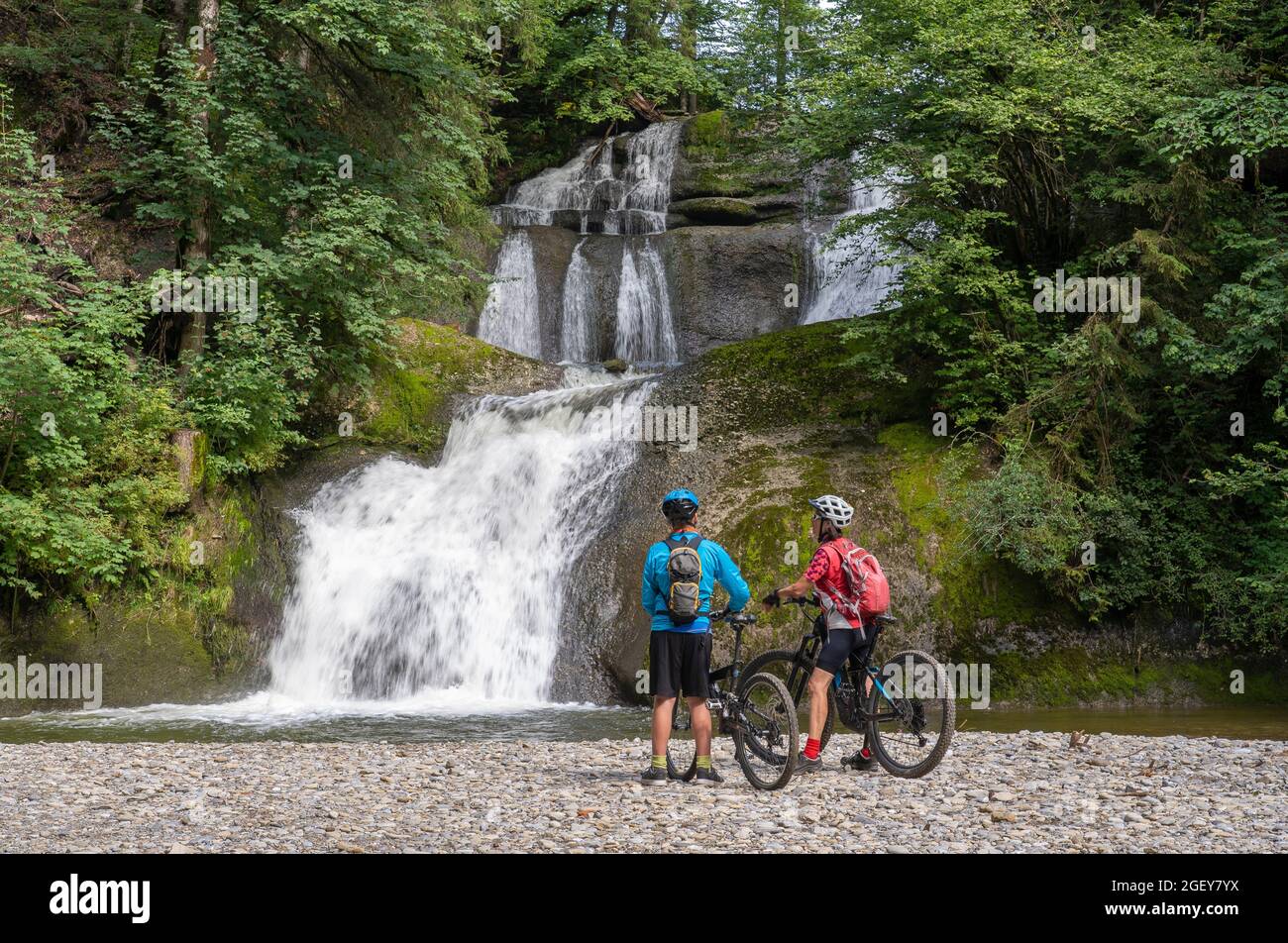 Une jeune grand-mère heureuse et son petit-fils se mettent en route avec leurs VTT électriques dans les Alpes d'Allgaeu, dans une chute d'eau près d'Oberstaufen, dans les Alpes bavaroises Banque D'Images