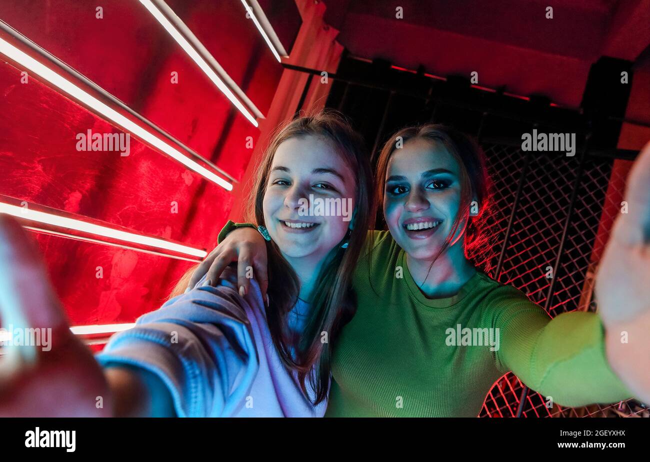 Portrait de selfie de deux bonnes amies, jeunes filles avec maquillage naturel dans des vêtements élégants se tenant les uns aux autres par les épaules, s'amusant à di Banque D'Images