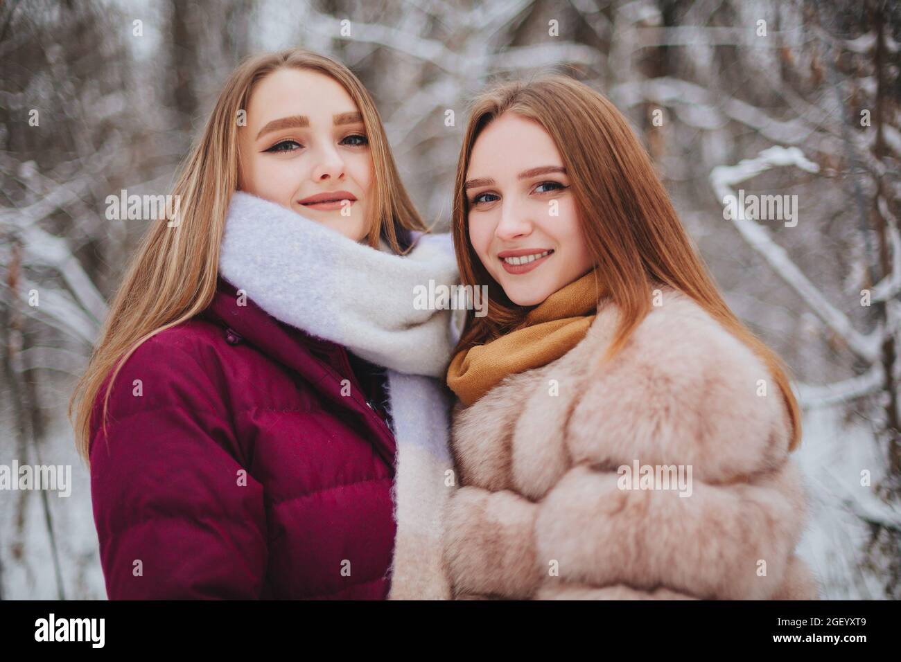 Deux amies joyeuses qui apprécient le temps de neige en plein air, les meilleures amies en hiver vêques en duvet vestes riant et s'amusant en marchant Banque D'Images