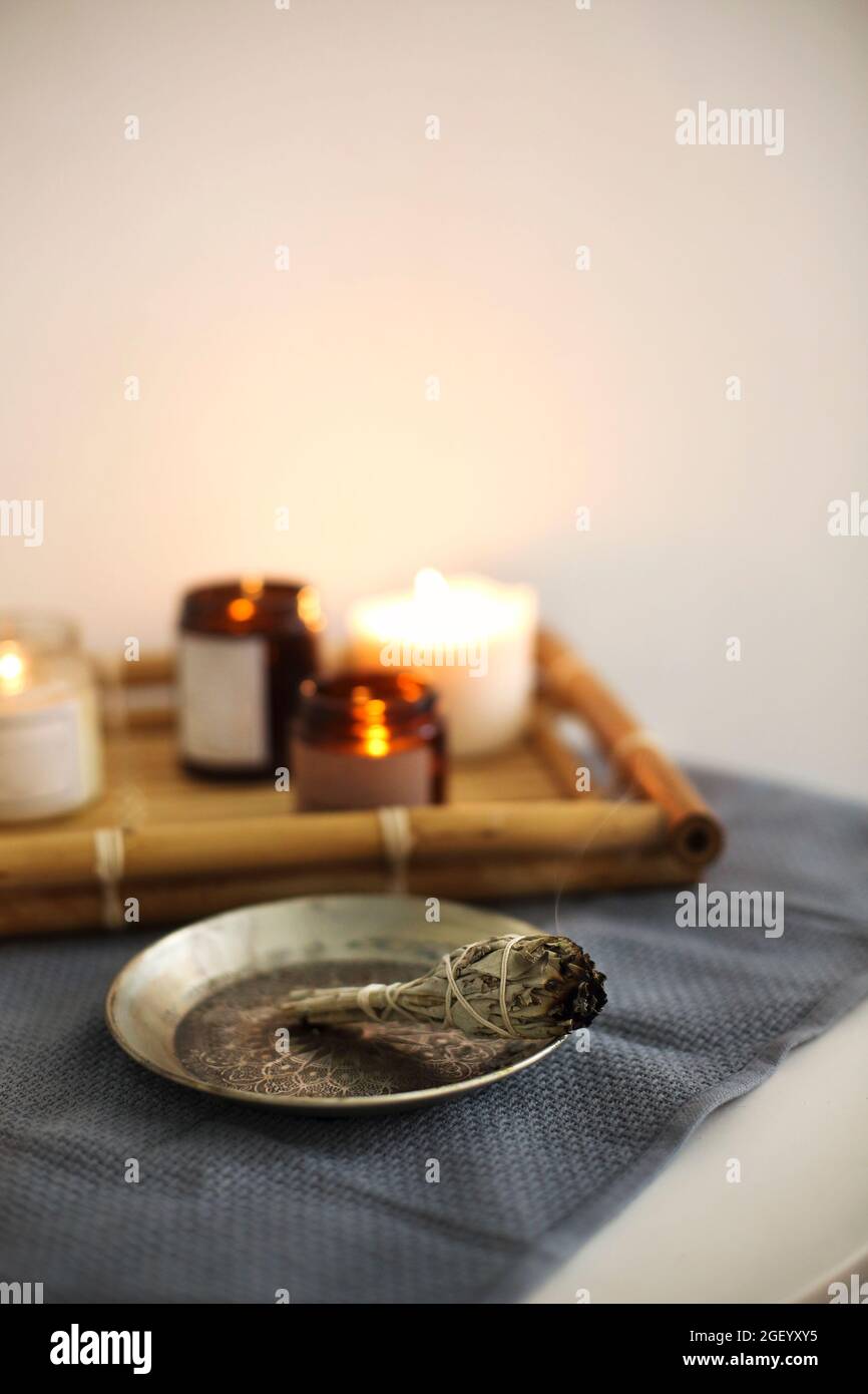 Encens pour fumigation, branches de sauge blanche liées en bouquet de fleurs séchées, bâton d'odeur d'arôme brûlant sur plaque métallique, aromathérapie et méditatio Banque D'Images