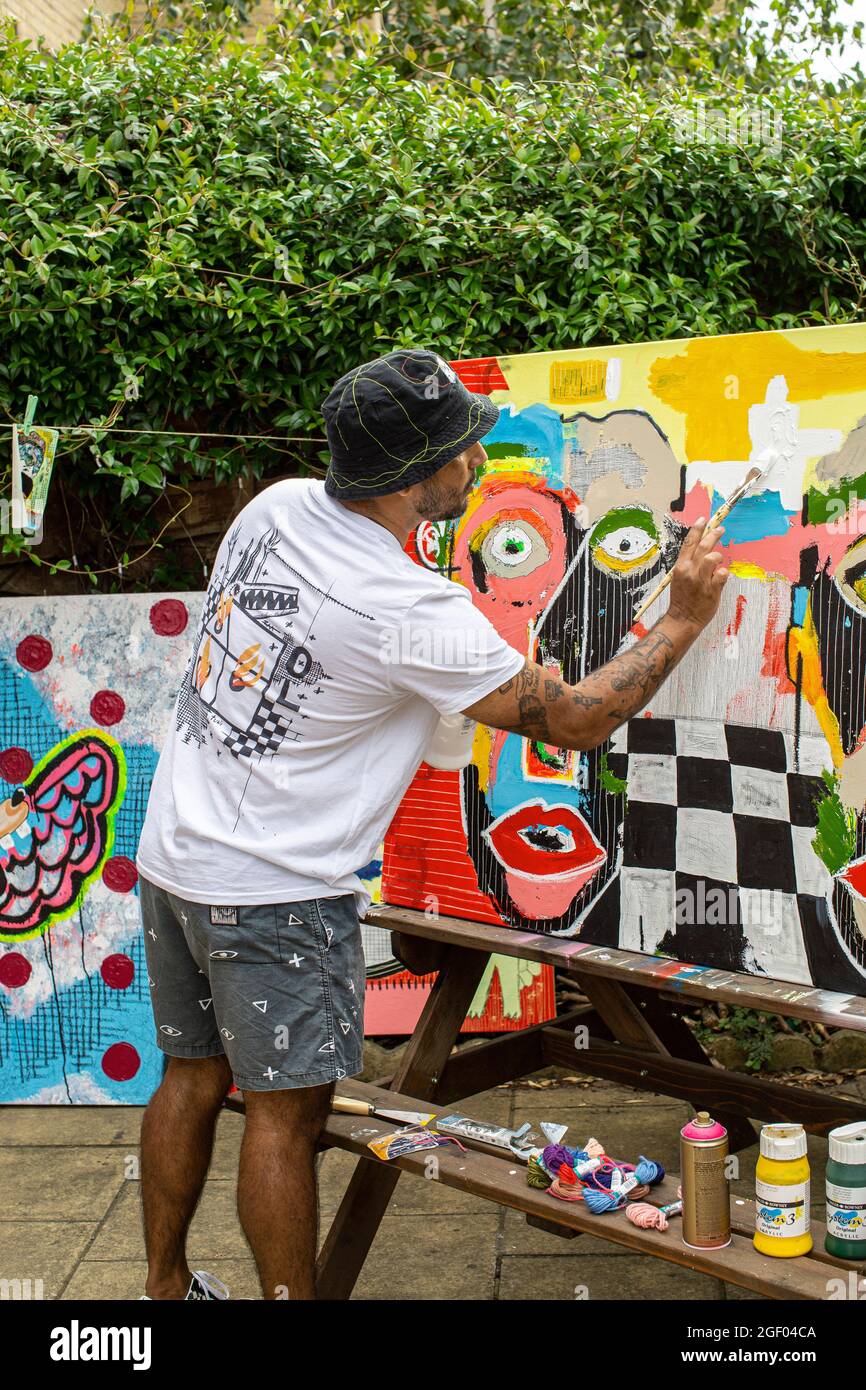 Jeune artiste masculin finissant sa peinture sur toile debout dans un jardin. Banque D'Images