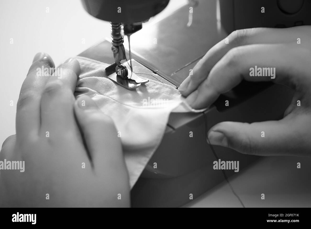 Un gros plan échelle de gris d'une personne qui coud un tissu avec la machine à coudre Banque D'Images