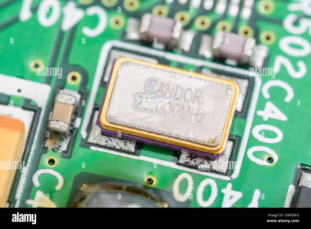 Macro de SM / oscillateur à quartz métallique à montage en surface sur une carte de circuit imprimé. Évalué à 25Mz et fabriqué par Candor (société chinoise). Banque D'Images