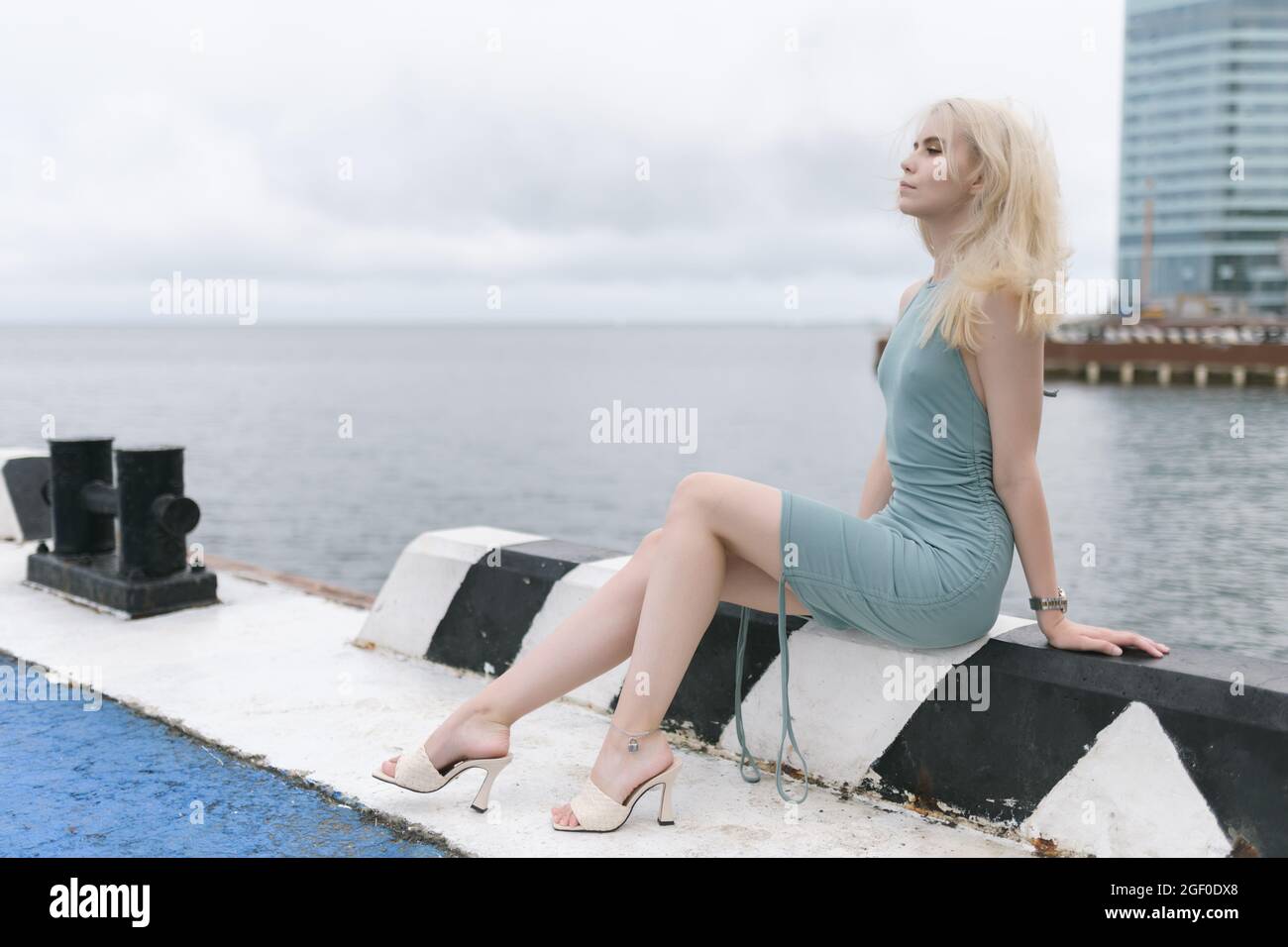 Femme en robe bleue aime la mer sur la jetée. Banque D'Images