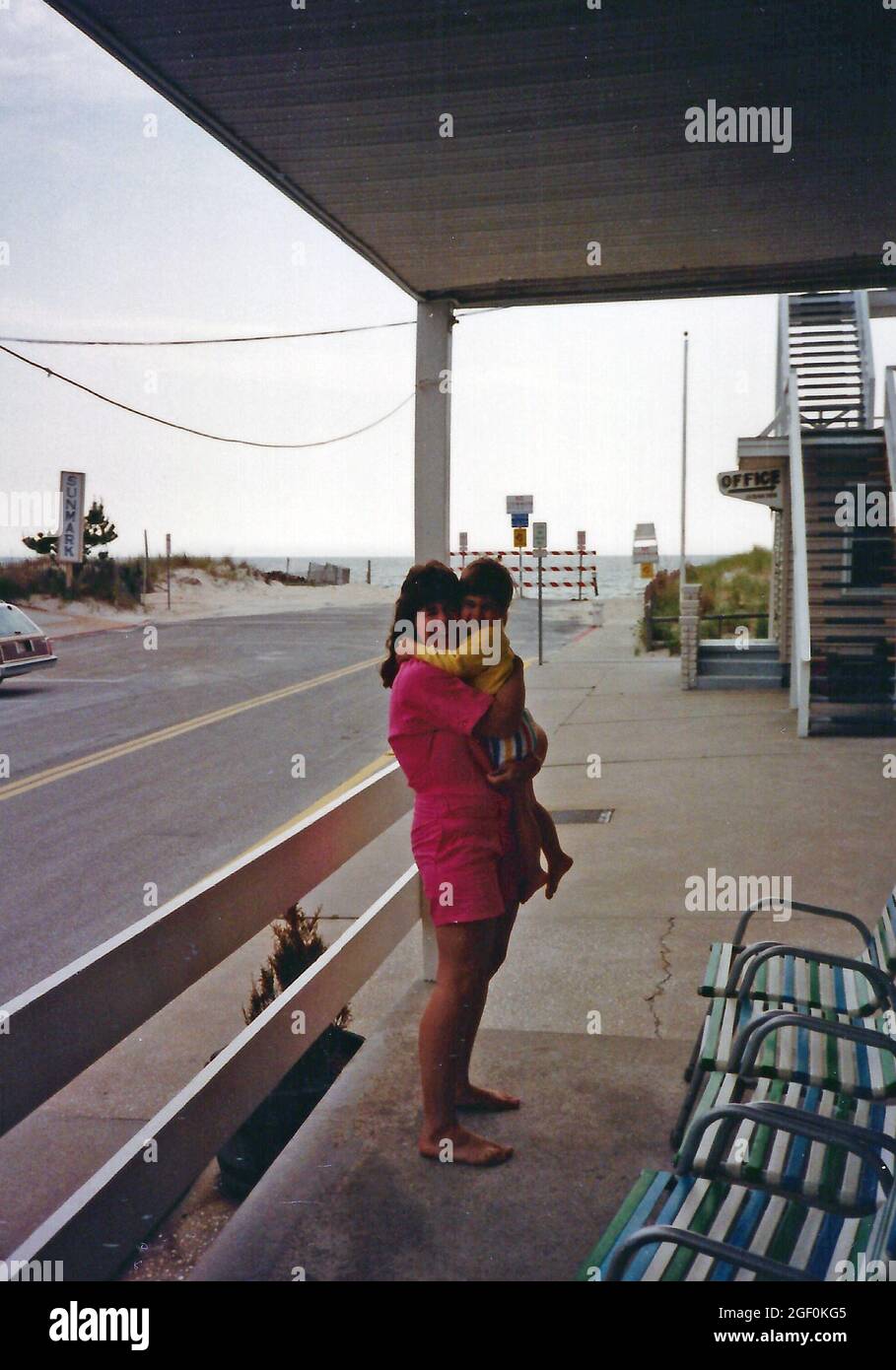 Une jeune femme et une petite fille qui s'embrasse devant un hôtel sur la plage d'Ocean City, Maryland, vers 1988 Banque D'Images