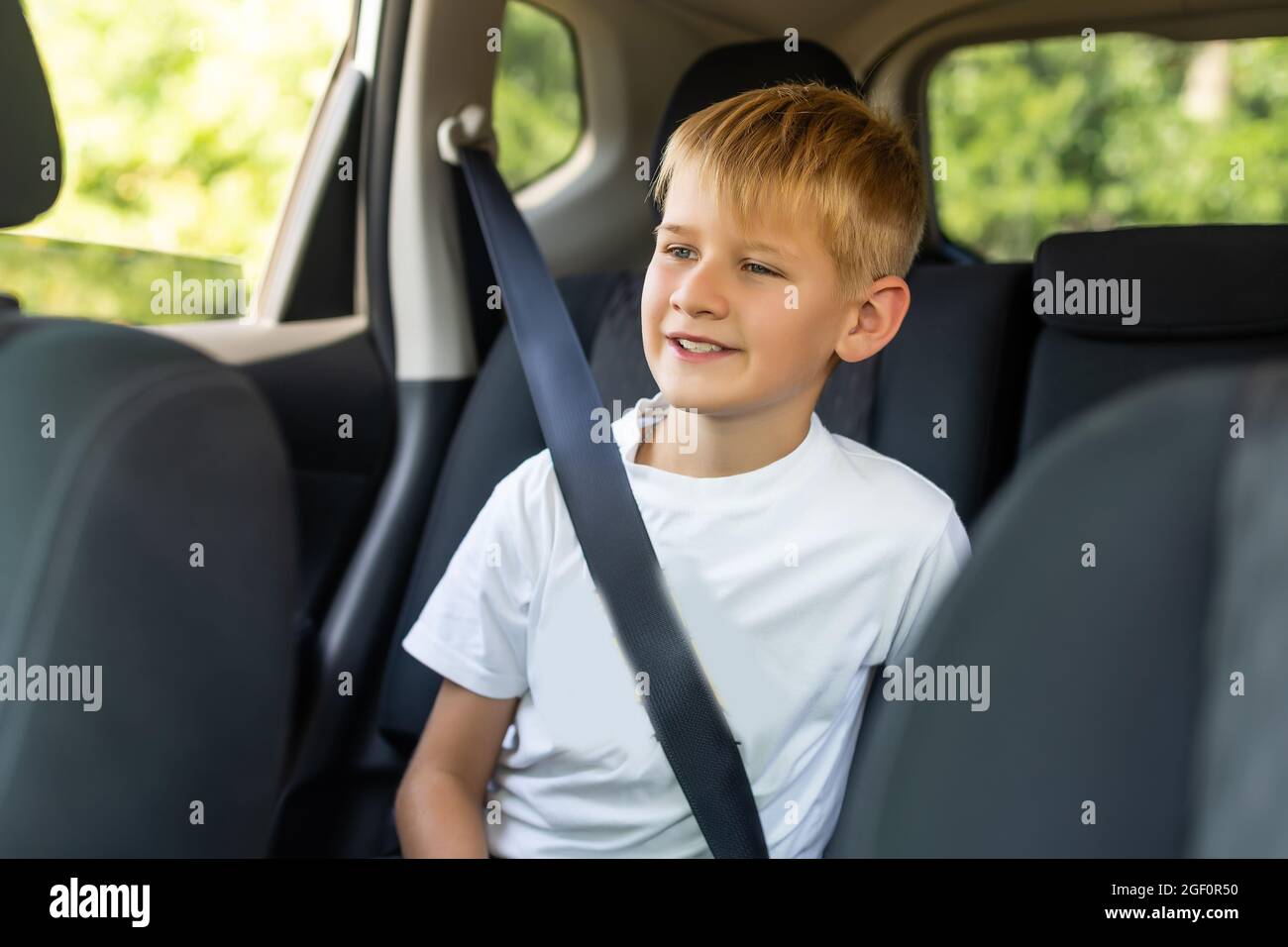 Jeune garçon bouclé avec ceinture de sécurité à l'intérieur de la voiture  Photo Stock - Alamy