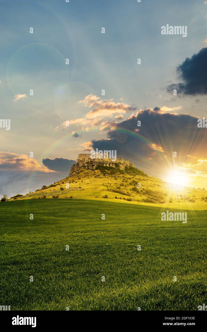 château sur la colline sous un arc-en-ciel au coucher du soleil. paysage de fantaisie composite. prairie herbacée en premier plan. sommets rocheux de la crête au loin Banque D'Images château sur la colline sous un arc-en-ciel au coucher du soleil. paysage de fantaisie composite. prairie herbacée en premier plan. sommets rocheux de la crête au loin Banque D'Images