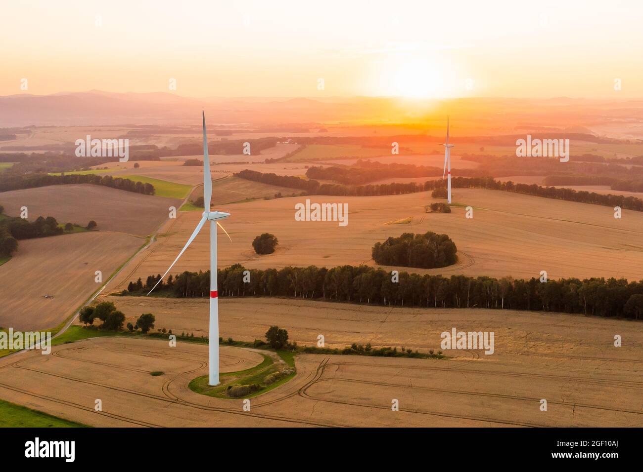 Vue panoramique sur les moulins à vent ou les éoliennes pour la production d'électricité à un coucher de soleil étonnant sur le terrain. Production d'énergie renouvelable verte. Banque D'Images