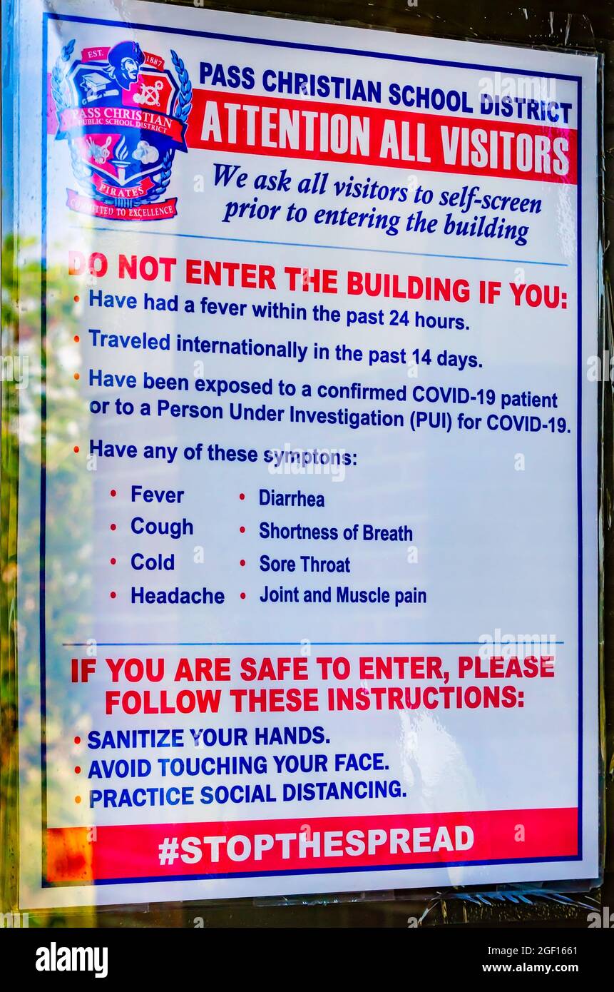 Un panneau COVID-19 à la Pass Christian High School invite les visiteurs à ne pas entrer dans le bâtiment s'ils ont des symptômes de COVID-19 ou s'ils y ont été exposés. Banque D'Images