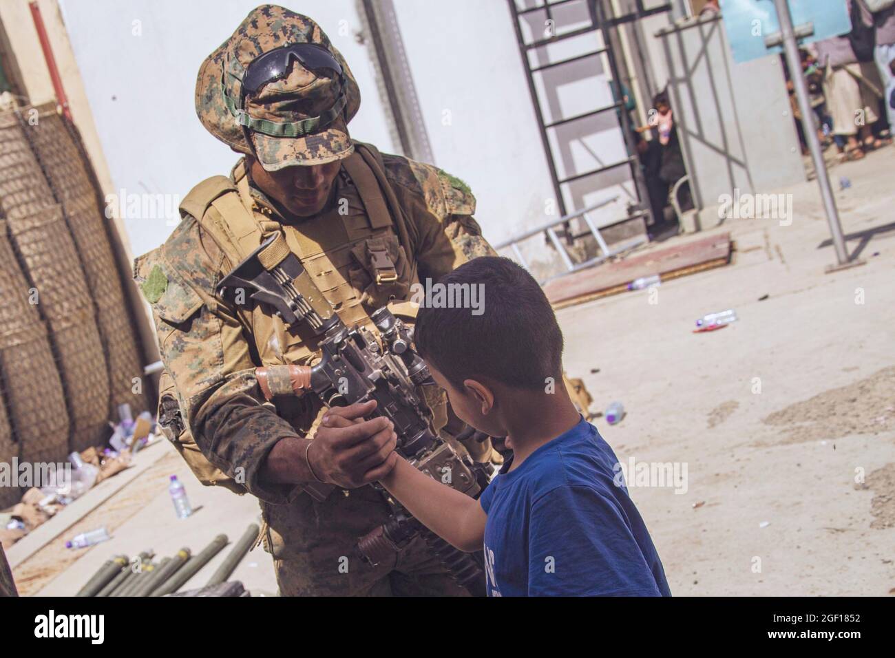 Kaboul, Afghanistan. 21 août 2021. Un Marine américaine affecté à la 24e unité expéditionnaire maritime, enseigne à un enfant afghan comment établir une liaison en attendant l'évacuation à l'aéroport international de Hamid Karzaï pendant le refuge de l'opération alliés le 21 août 2021 à Kaboul, en Afghanistan. Credit: Planetpix/Alamy Live News Banque D'Images