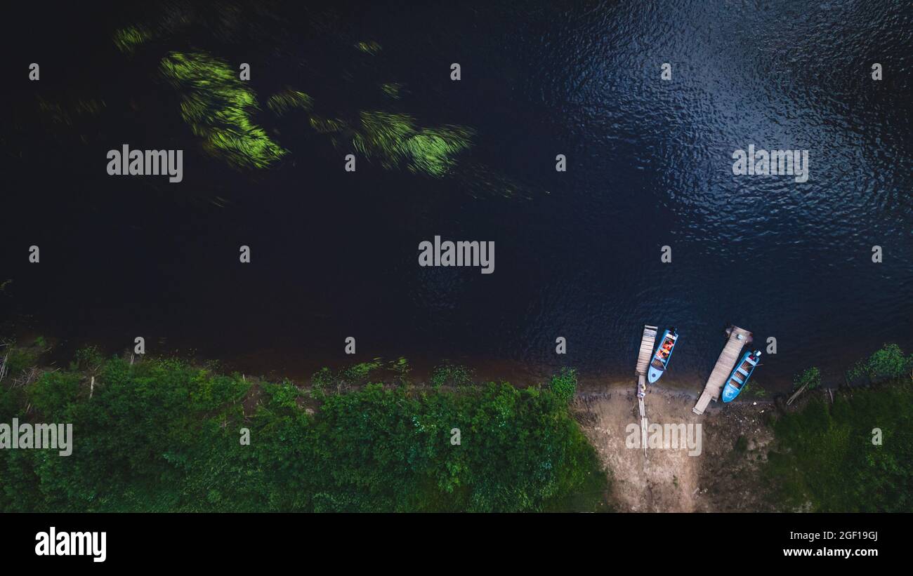Deux bateaux sont amarrés à la rive sur l'eau sombre d'une rivière ou d'un lac, vue de dessus. Faune, climat planétaire. Direction du tourisme, du voyage Banque D'Images